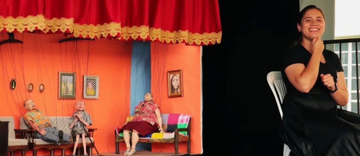 Espetáculo teatral com cenário colorido e intérprete de Libras atuando na lateral do palco.